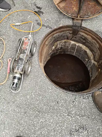CCTV crawler camera robot beside an open sewer manhole, ready for pipe inspection